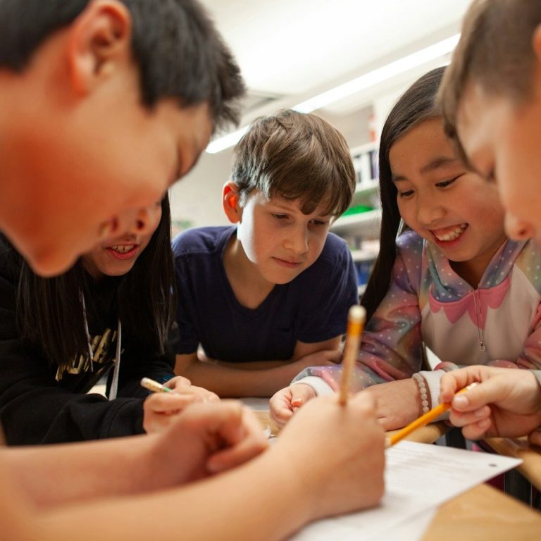 Group of diverse children focused on a collaborative drawing activity.